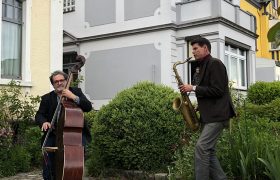 Zwei Männer machen Musik in einem Vorgarten.