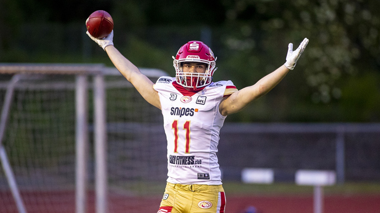 Ein Footballspieler der Lübeck Cougars hält mit erhobenen Armen einen Football