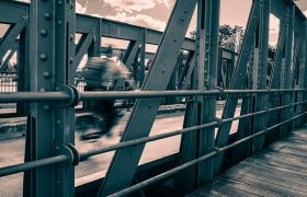Durch die Stahlstreben der Drehbrücke sieht man einen Fahrradfahrer mit starker Bewegungsunschärfe