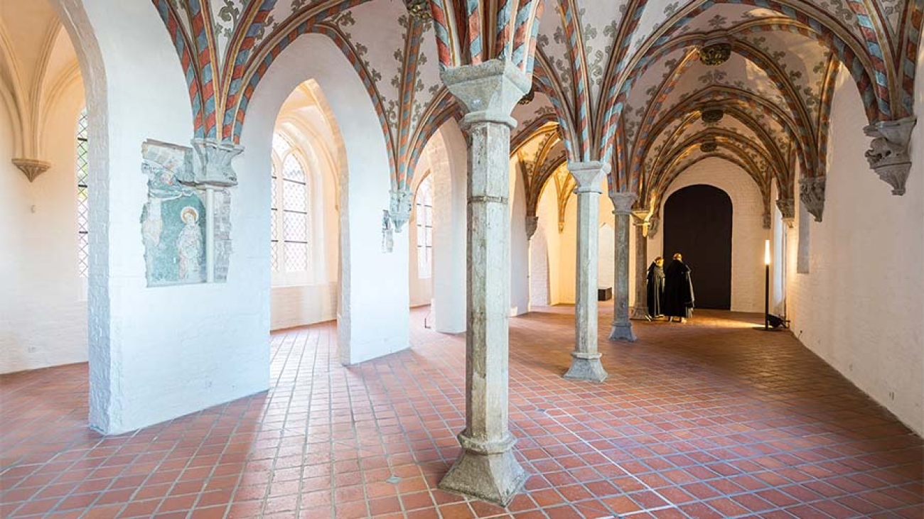 Ein Blick in das Burgkloster im Europäischen Hansemuseum: Weiße Wände mit gotischem Gewölbe und Backstein-Fußboden