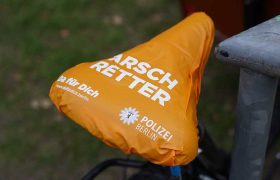 Auf einem orangefarbenen Sattelschoner steht groß "Arschretter" und kleiner "Polizei Berlin"
