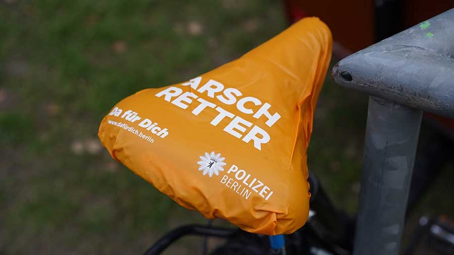 Auf einem orangefarbenen Sattelschoner steht groß "Arschretter" und kleiner "Polizei Berlin"