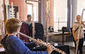 Drei Musiker üben in einem Raum mit unterschiedlich großen Querflöten