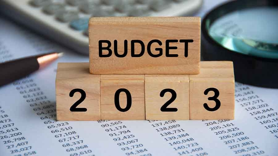 Auf einer Liste mit Zahlen stehen Holzwürfel, auf denen "Budget 2023" steht. Im Hintergrund liegen Lupe, Kugelschreiber und Taschenrechner.