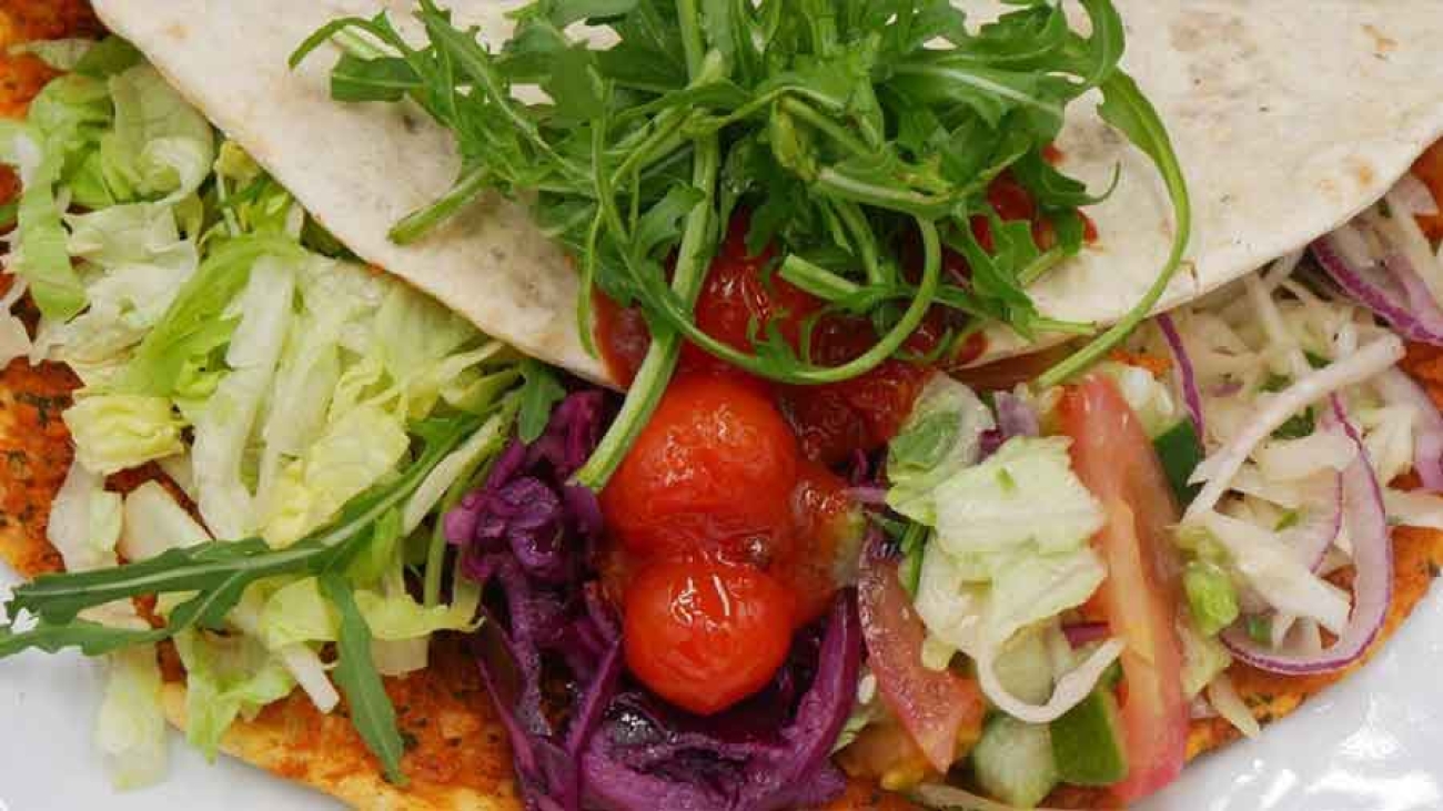 Detailaufnahme einer mit Tomaten, Kraut und Salat belegten Lahmacun