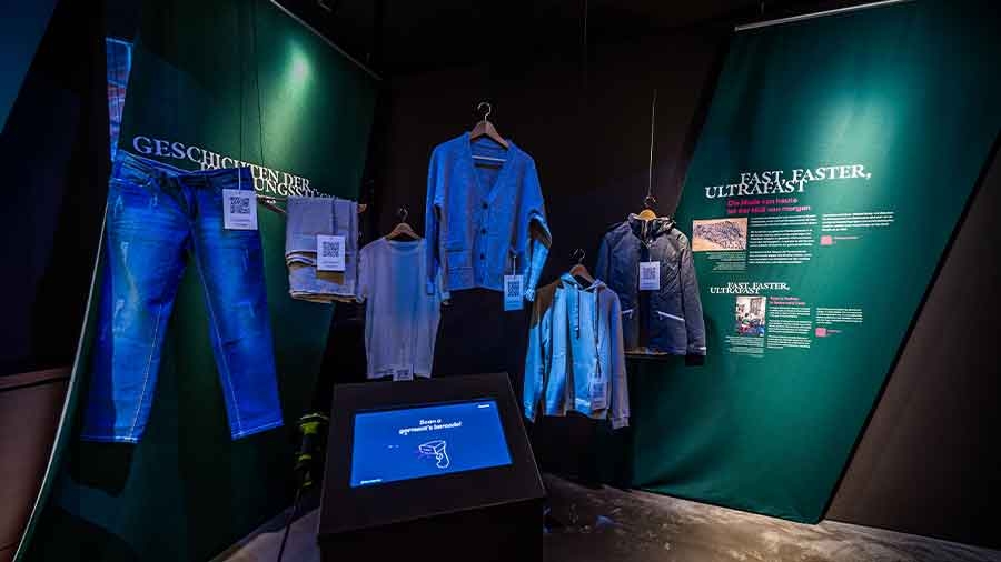 Einige blaue Kleidungsstücke hängen in einer Museumsumgebung