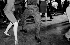 Zusehen sind die Beine von Swing-Tänzern und Tänzerinnen in schwarz-weiß.