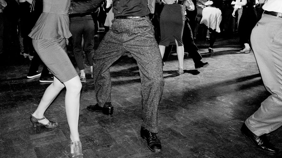 Zusehen sind die Beine von Swing-Tänzern und Tänzerinnen in schwarz-weiß.