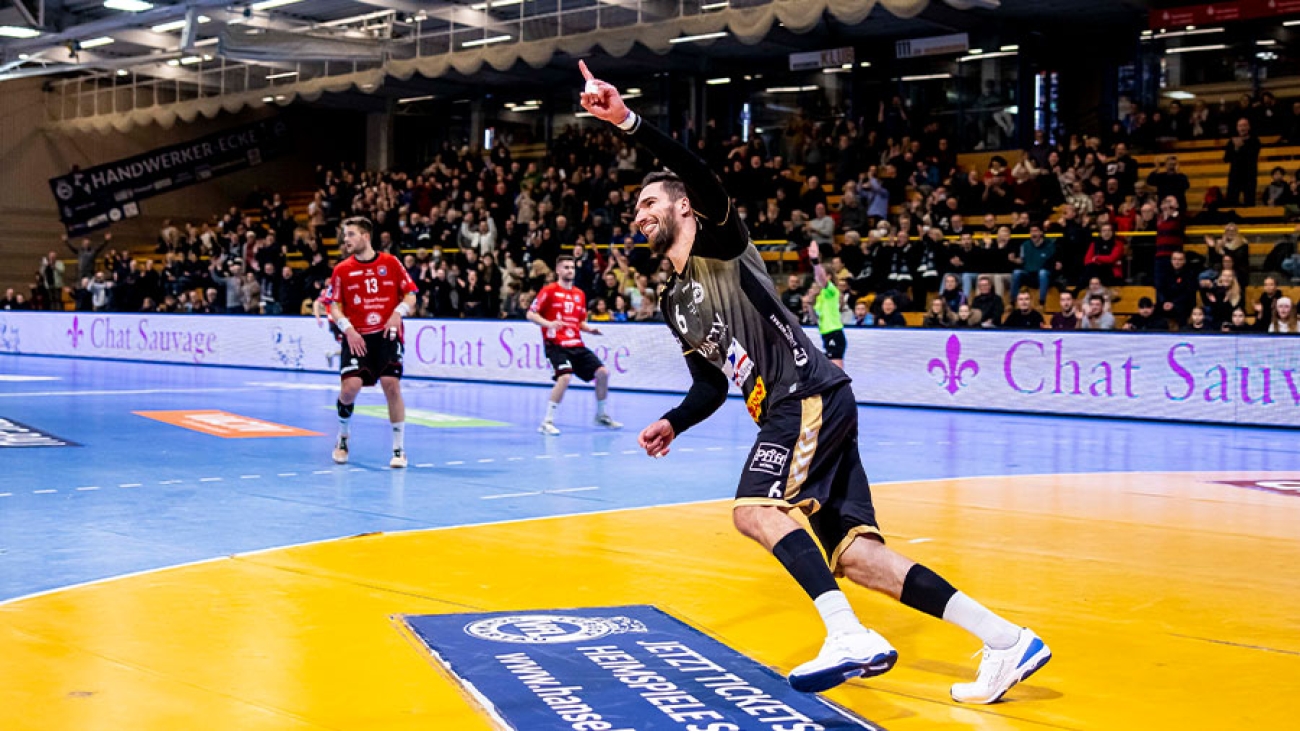 Ein Spieler des VfL Lübeck-Schwartau läuft jubelnd vom Torkreis los. Zwei Gegenspieler in roten Trikots stehen im Hintergrund