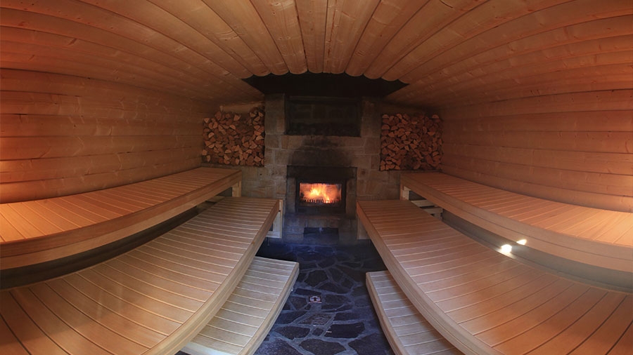 Blick ins Innere einer Sauna, ein Feuer brennt, die Bänke sind leer