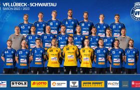 Ein Mannschaftsbild des VfL Lübeck-Schwartau: 22 Spieler stehen aufgereiht vor blauem Hintergrund. Bis auf drei Torwarten mit gelben Trikots tragen die Männer blaue Trikots mit weißen Nummern. Rechts und links stehen zwei Betreuer mit grauen Pullovern