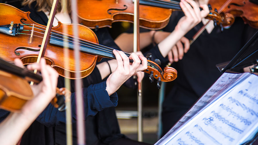 Mehrere Geigen werden in einem Orchester gespielt.