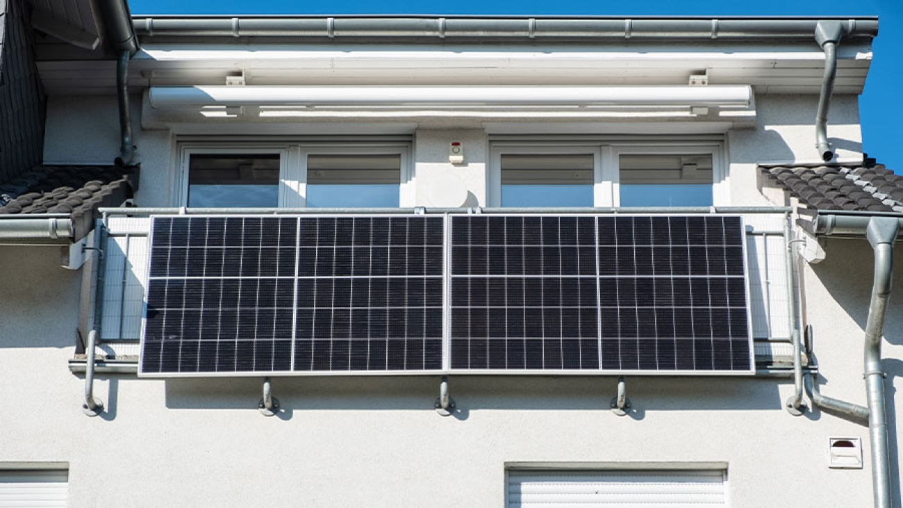Am sonnebeschienenen Balkon eines Hauses hängen zwei Solar-Module