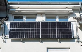 Am sonnebeschienenen Balkon eines Hauses hängen zwei Solar-Module