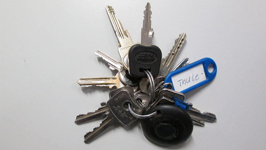 Ein Schlüsselbund mit mehreren Schlüsseln, einem runden schwarzen Transponder und einem blauen Schild mit der Aufschrift "Thule"