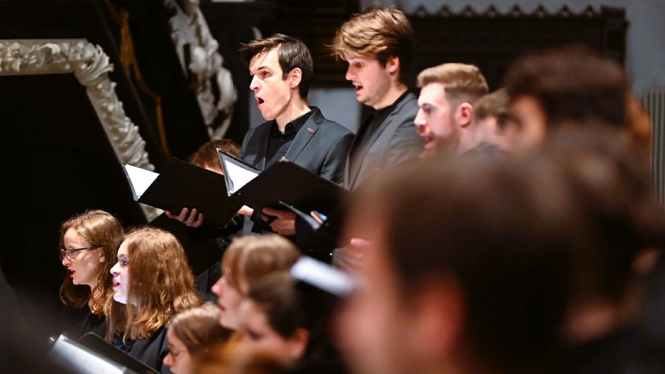 Mehrere schwarz gekleidete Musikstudenten singen im Chor.