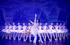 Balletttänzerinnen und ein Tänzer tanzen das berühmte Stück Schwanensee.
