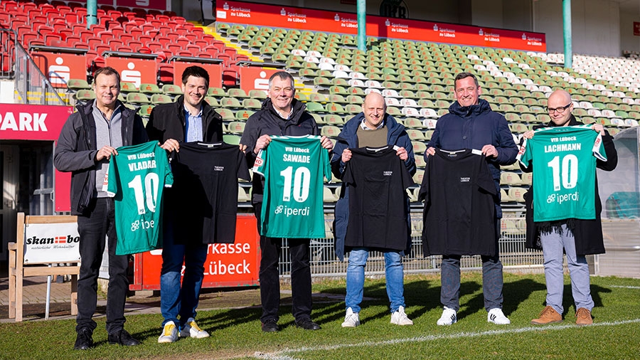 Vertreter des VfB und Theater Lübecks halten Trikots des Vereins.
