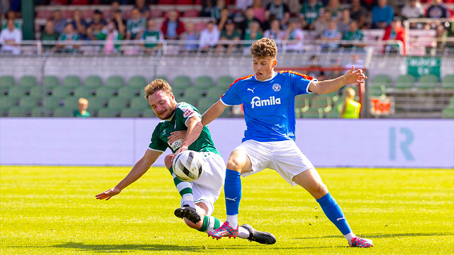 Zwei Fußballer kämpfen um den Ball, einer ist vom VfB Lübeck, der andere von Holstein Kiel.
