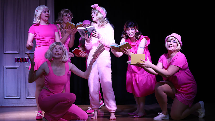 Mehrere Frauen in pinken Klamotten stehen gemeinsam auf der Bühne.