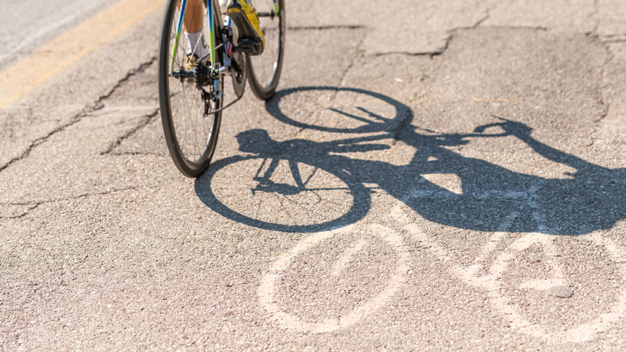 Ein Rennrad fährt über ein beschädigten Fahrradweg.