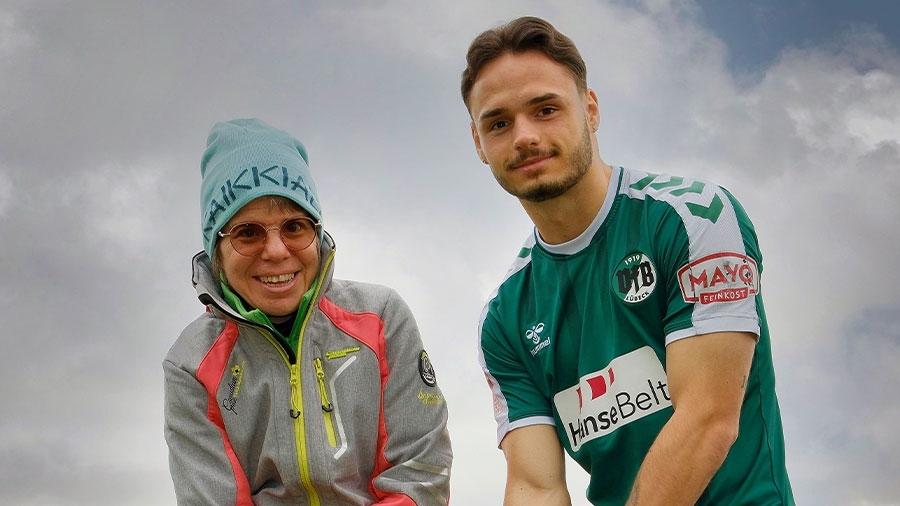 Ein ältere Frau und ein Spieler des VfB Lübeck lächeln in die Kamera.