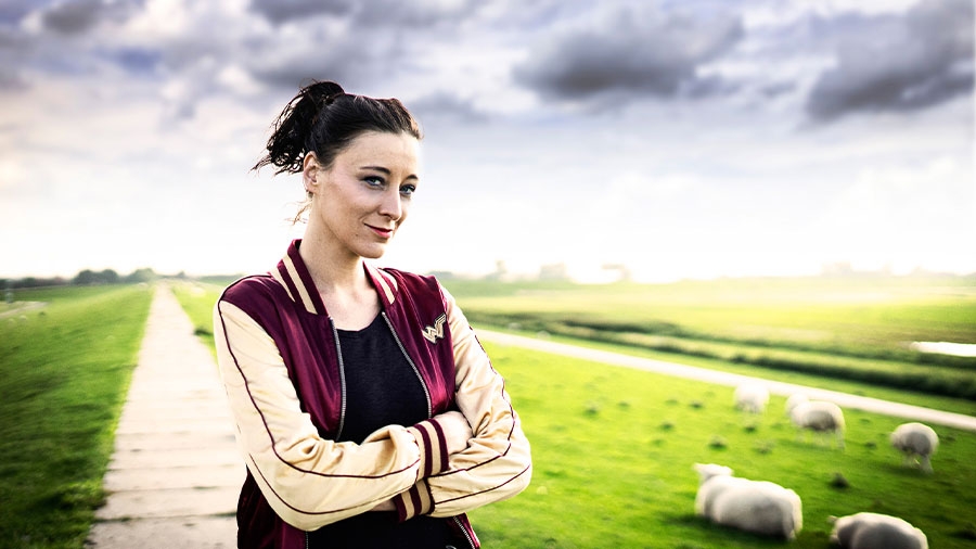Eine Frau steht auf einem Priwall mit Schafen.