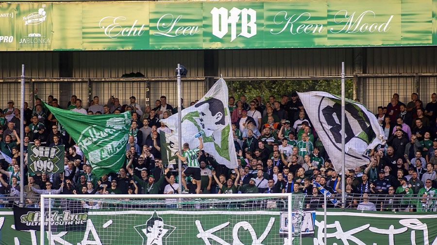 Die Fan-Tribüne des VfB Lübecks mit reichlich Fans und Fahnen in weiß und grün.