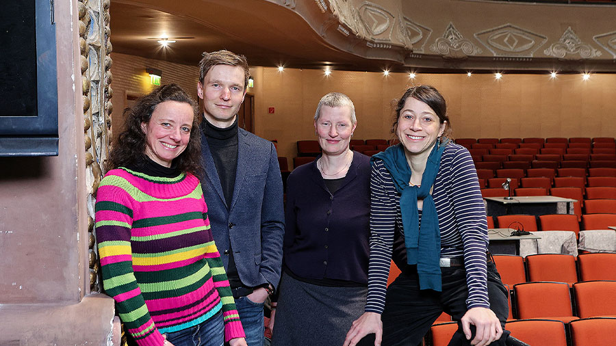 Drei Frauen und ein Mann stehen im Saal des Theater Lübecks und lächeln in die Kamera.