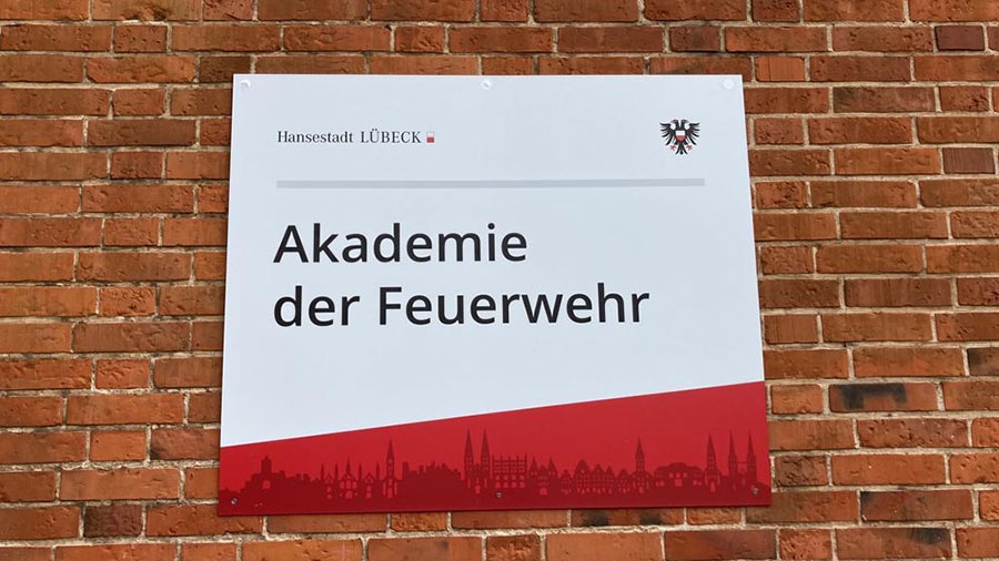 Ein Schild der Hansestadt Lübeck auf dem steht "Akademie der Feuerwehr".