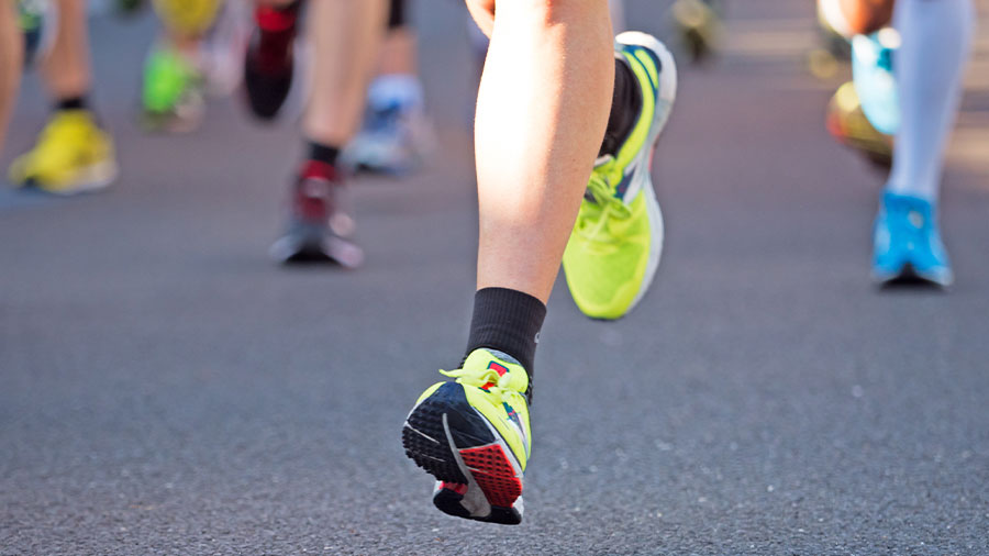 Zu sehen sind mehrere Beine von Personen, die einen Marathon laufen.