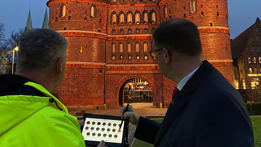 Lübecks Bürgermeister ändert auf einem IPad das Licht, das das Holstentor anstrahlt.
