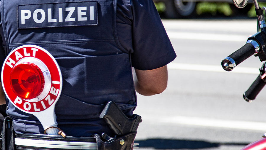 Ein Polizist steht auf der Straße an seinem Gürtel hängt eine Kelle der Polizei.