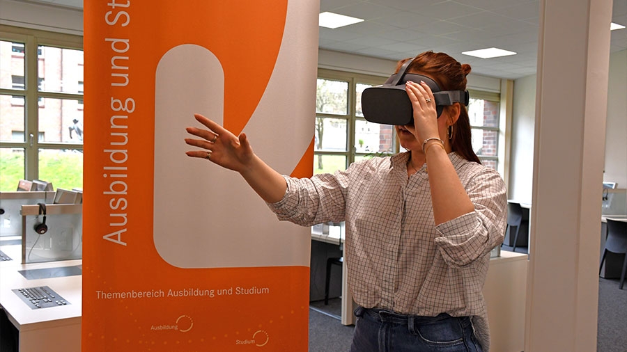 Eine Frau mit VR-Brille schlendert durch durch die Arbeitsagentur.