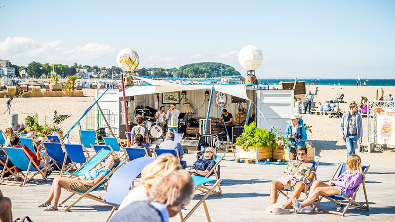 Mehrere Personen entspannen auf Strandliegen in der Sonne.