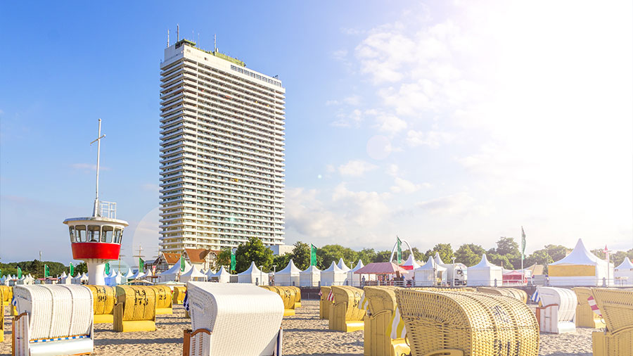 Das bekannte Hotel am Travemünder Strand im Sonnenschein. Im Vordergrund stehen noch Strandkörbe.