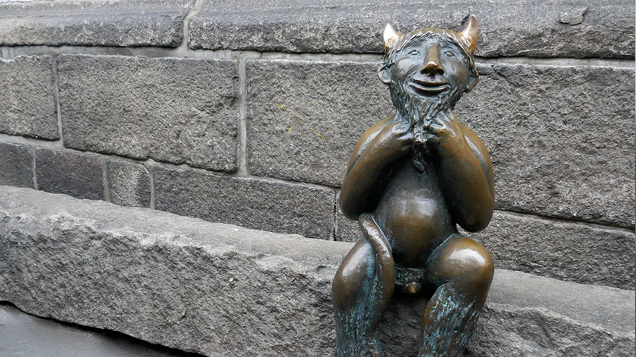 Ein Teufel sitzt auf einem Stein vor einer Kirche in Lübeck.