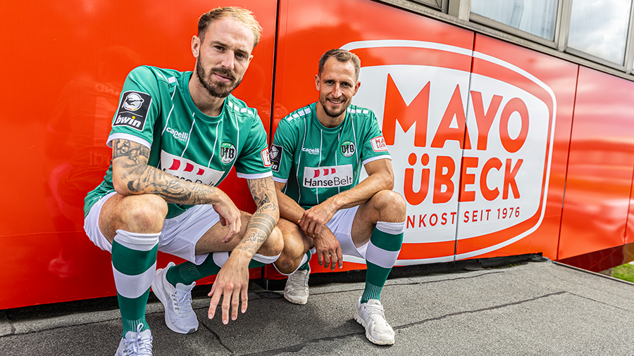 VfB Fußballspieler vor einer Mayo Lübeck Tafel.