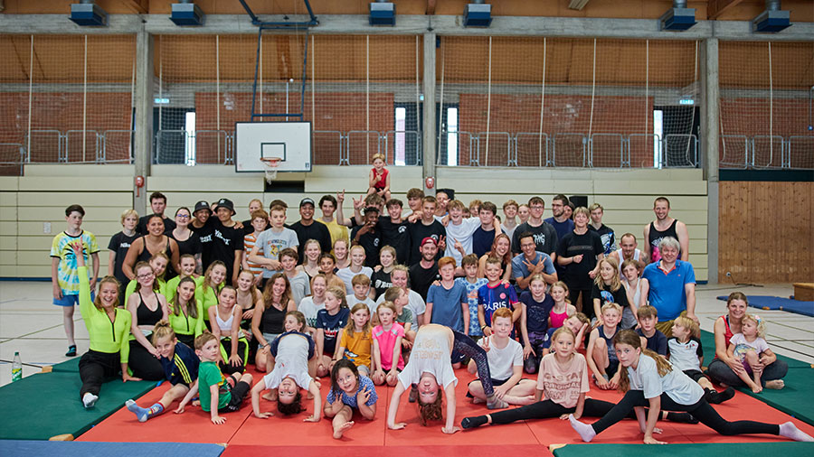 Eine Gruppe Kinder auf Turnmatten in einer Turnhalle.