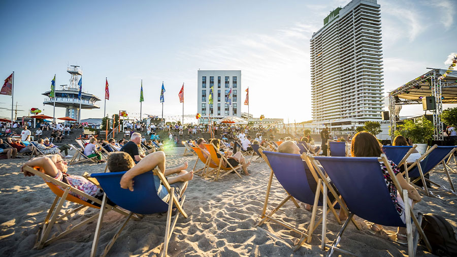 Eine Menge Menschen liegen auf Strandstühlen in der Sonne in Travemünde.