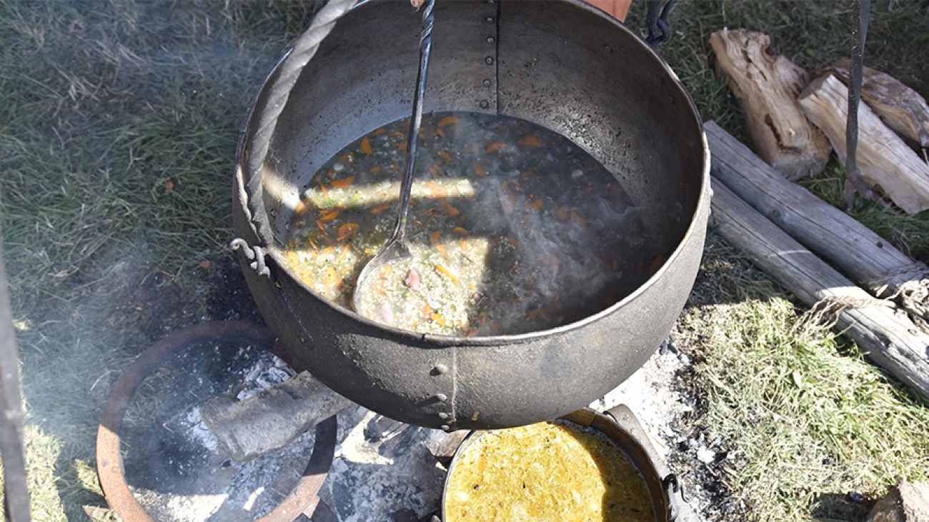 Ein Topf mit Suppe der über einem Feuer hängt.