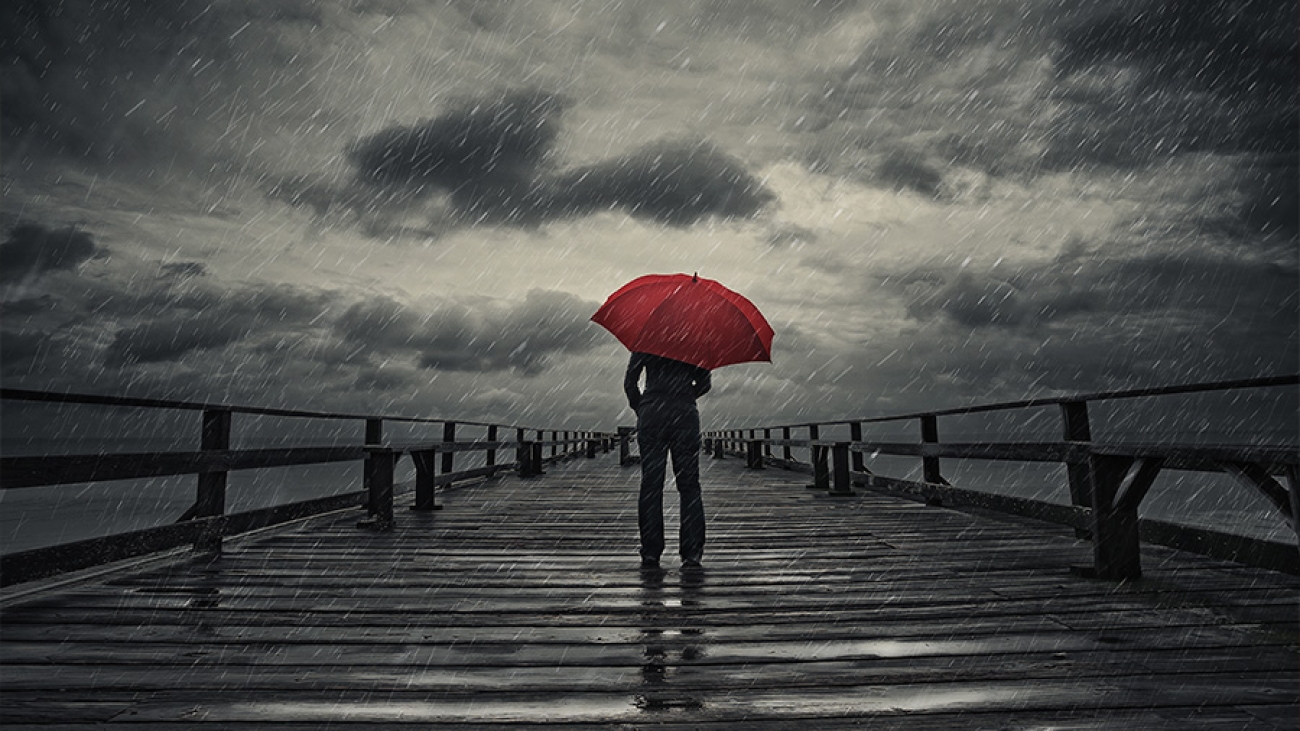 person mit Regenschirm auf einem Steg