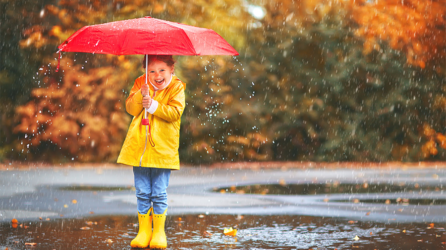 Kind im Herbst mit rotem Schirm