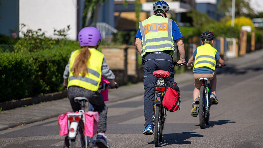 Ein Polizist der mit zwei Kindern Radfahren übt