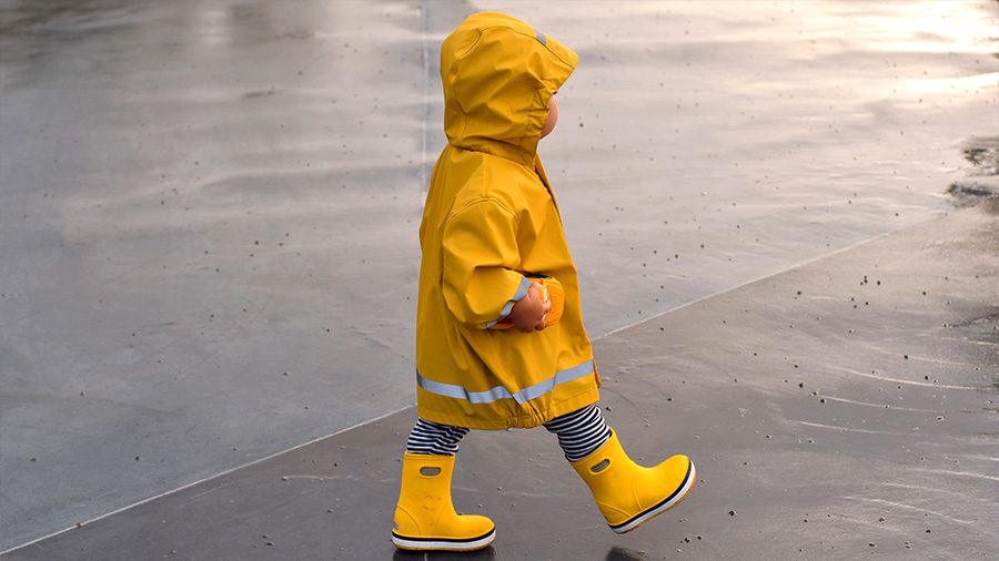 Kind mit Regenkleidung am Strand