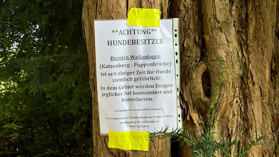 Aufgehängter Zettel mit Warnung für Hundehalter