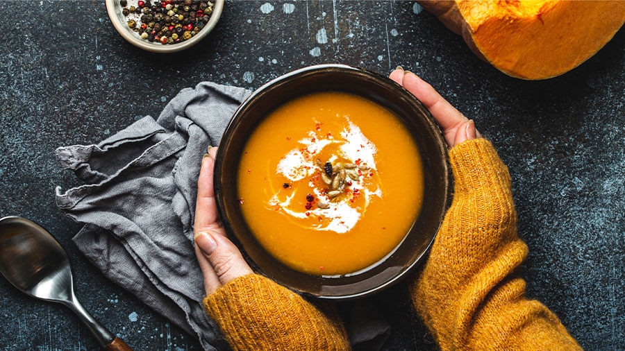 Ferige Suppe in einer Schüssel, gehalten von zwei Händen